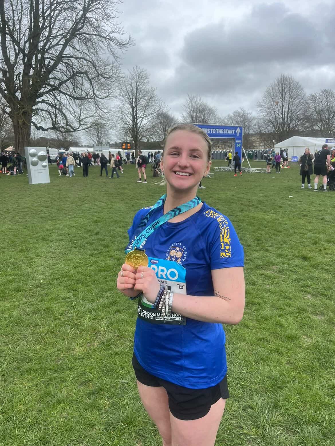 A photo of Isla holding a running medal after a race.