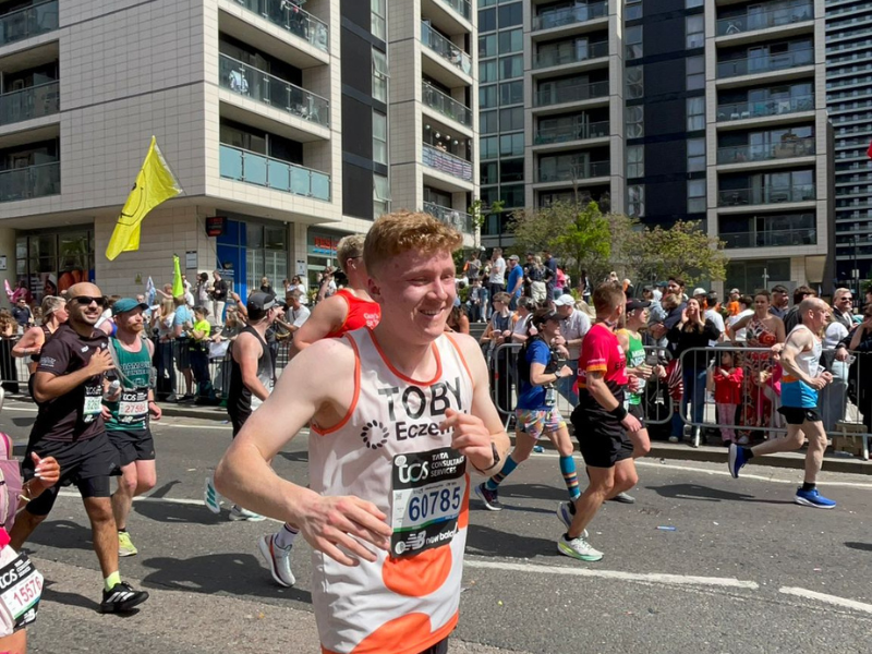 A runner in an eczema uk mid race smiling at the camera.
