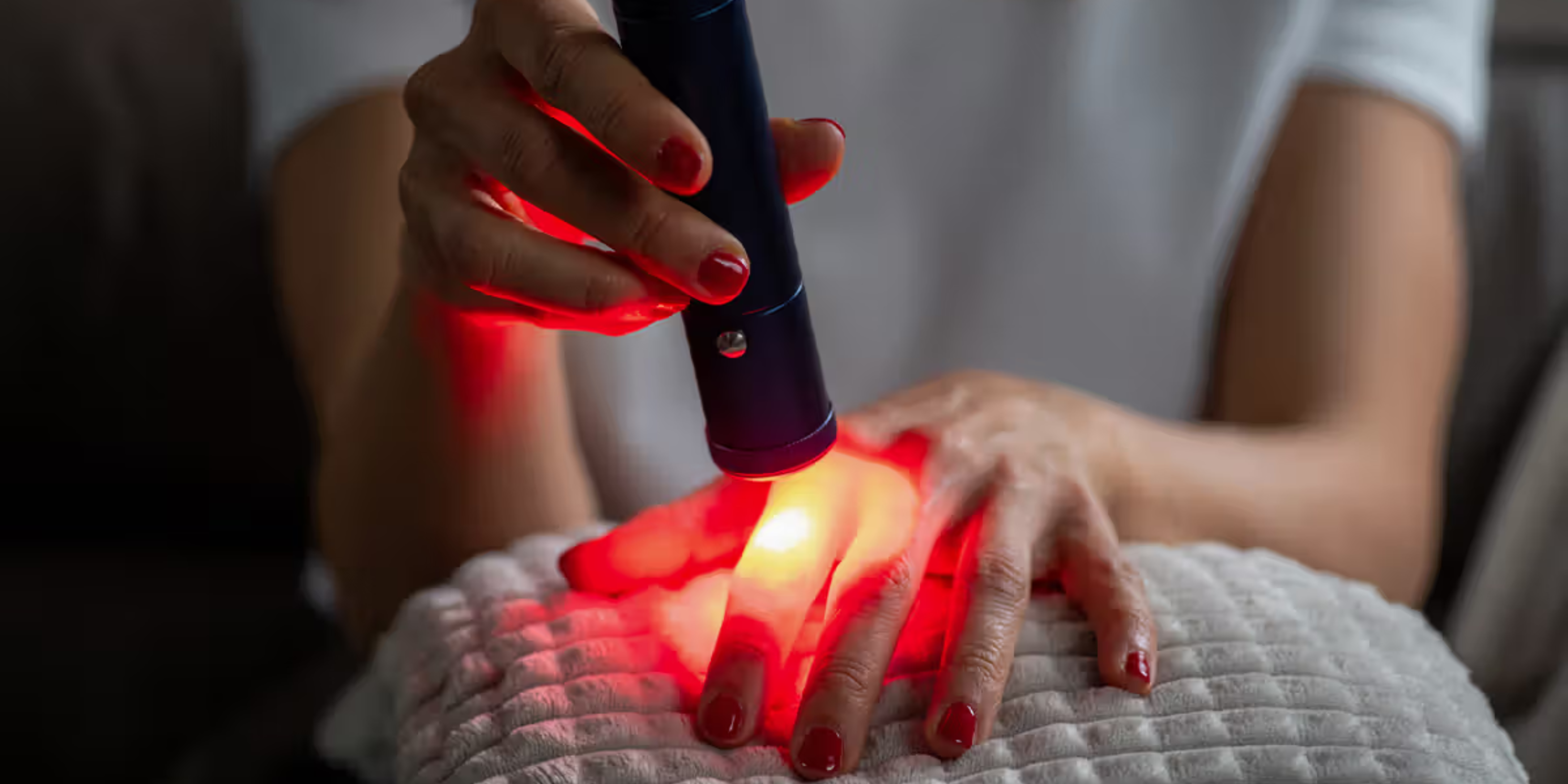 A picture of someone holding a red light over their hand as part of phototherapy treatment