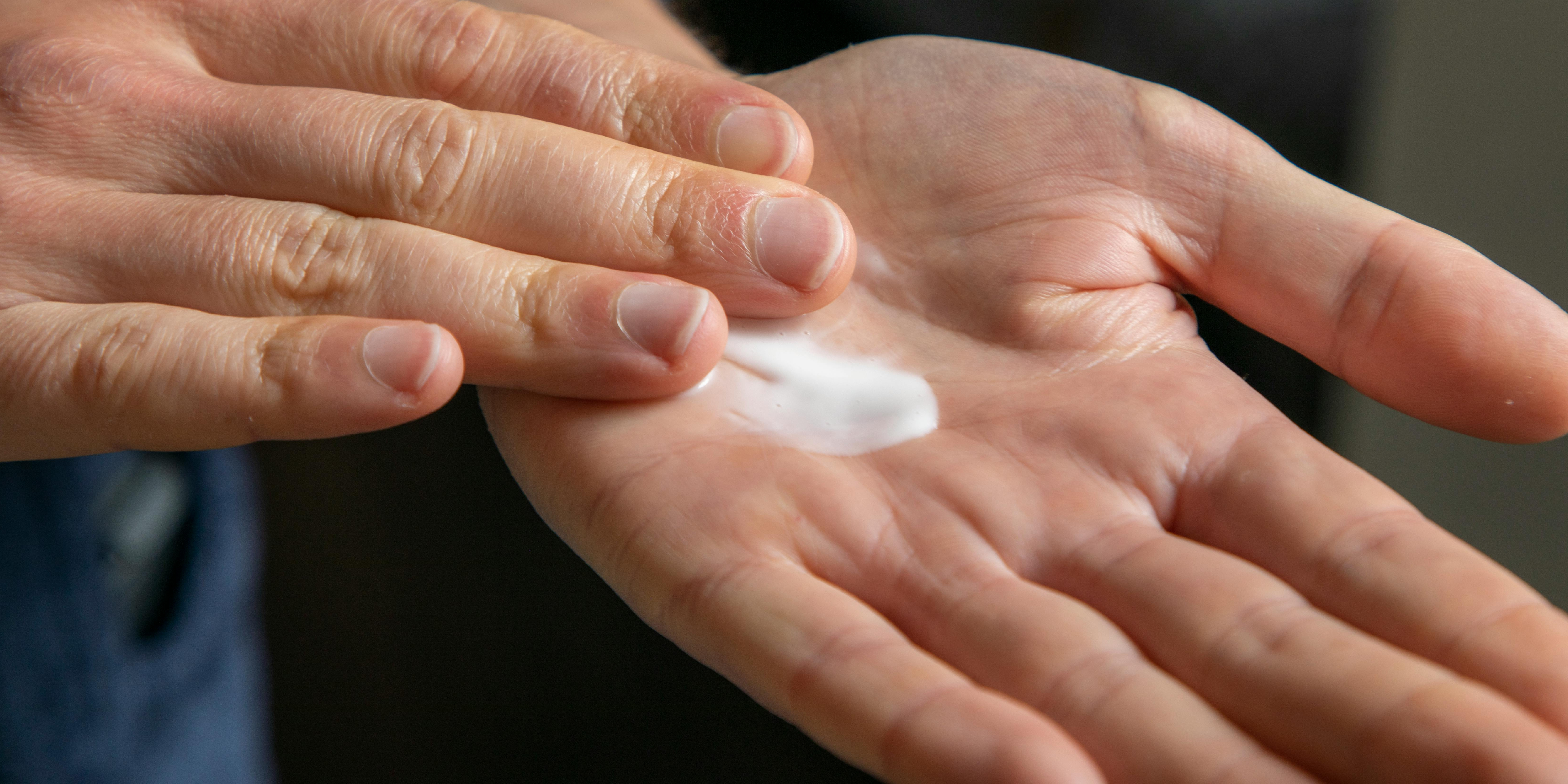 A person smoothing out emollient cream on their hand
